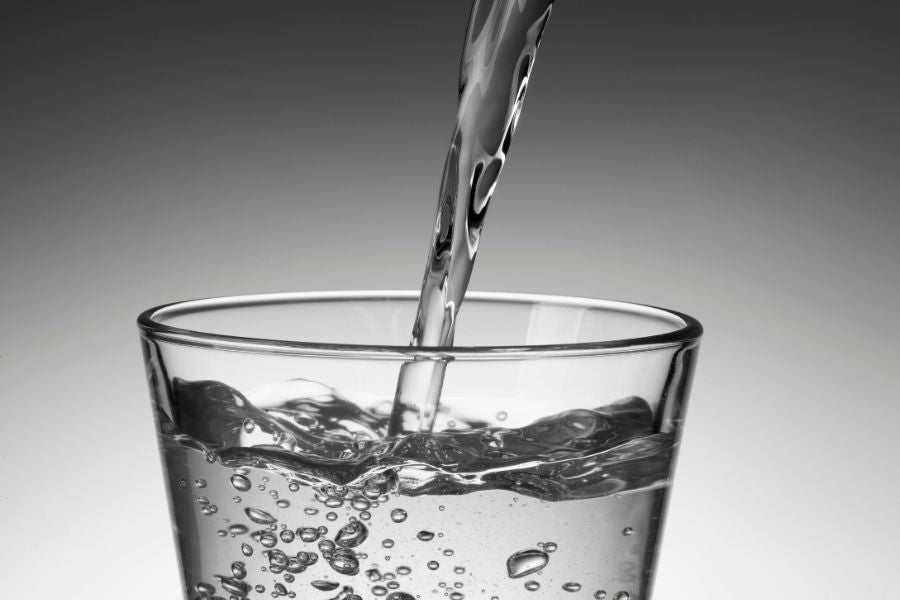 A glass of water being poured into a glass