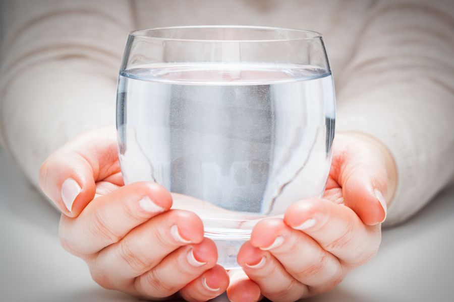 A person holding a glass of Alkaline water