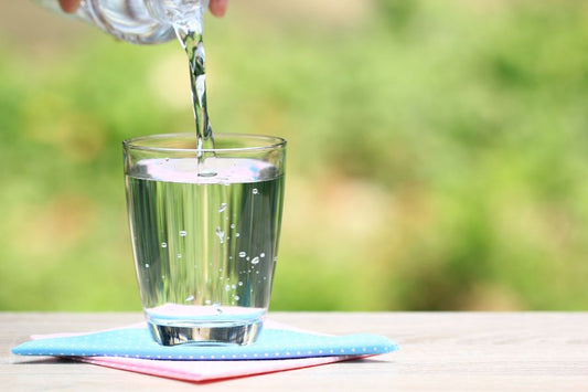 A hand pouring water into a glass